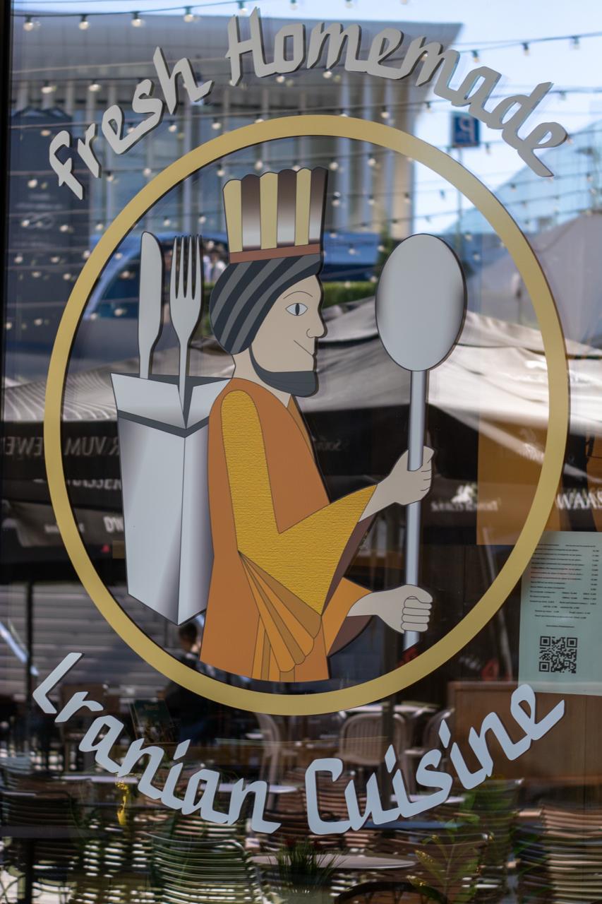 Scrambled eggs with tomatoes, olives, and meat in pan.